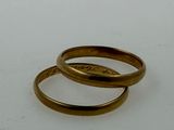 two gold rings that are sitting on a white surface