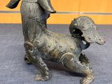 bronze statue of a dog with a long tail on a blue carpet
