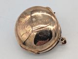 une petite montre de poche en argent posée sur une surface blanche