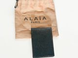 un portefeuille noir et un sac marron posés sur une surface blanche