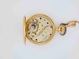 a gold pocket watch with a chain on a white surface
