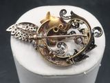a gold brooch with a cat and a bird on it