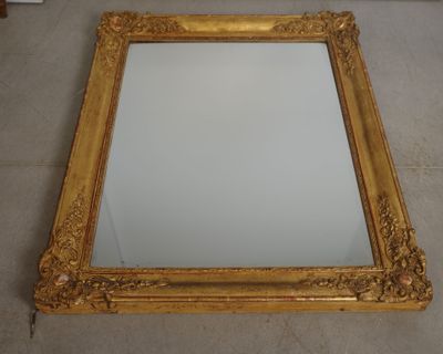 gold framed mirror on the floor with a white wall in the background