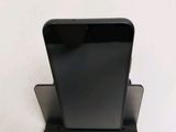 a black cell phone sitting on a stand on a white surface