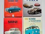 quatre livres posés sur une table blanche, avec un combi VW bleu et un combi VW rouge