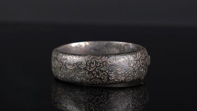gros plan d'une bague en argent sur une surface noire