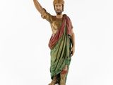 an old statue of a man with a hat on his head pointing at something