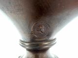 a silver vase that has a medallion on it