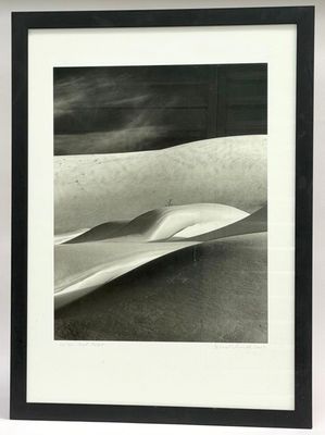 photographie en noir et blanc d'une planche de surf sur une plage de sable