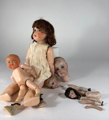 une poupée assise par terre, entourée d'autres poupées