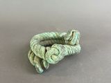a close up of a green rope bracelet on a gray surface