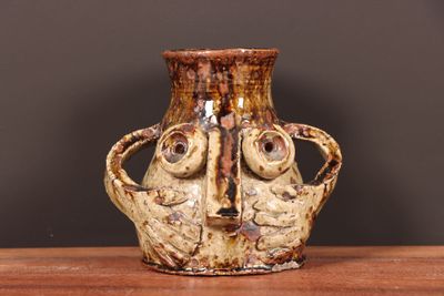 a vase with a face on it sitting on a table