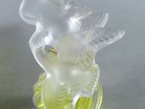 a glass figurine of a bird sitting on top of a leaf