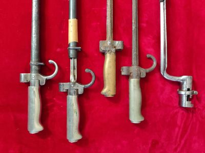 several different types of knives are lined up on a red cloth