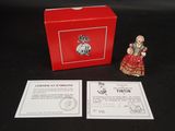 une petite figurine représentant une femme en robe rouge, à côté d'une boîte rouge