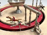 a miniature model of a carousel with horses and people on it