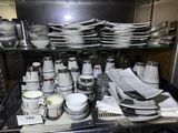 many plates and cups on a shelf in the kitchen