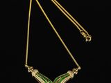a gold necklace with green and white enamel wings