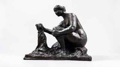 statue of a woman sitting on a rock with a dog