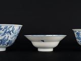 trois bols en porcelaine bleue et blanche sont alignés sur une surface noire