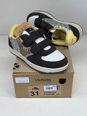 des baskets noires et blanches ornées d'un imprimé léopard, posées sur une boîte en carton