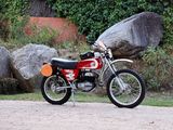 a red dirt bike parked next to a large rock