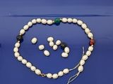 une photo d'un ensemble composé d'un collier et de boucles d'oreilles, posée sur un fond bleu