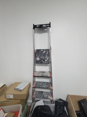 une échelle appuyée contre un mur, à côté d'une pile de cartons