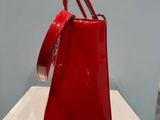 red handbag sitting on a white pedestal in front of a blue wall