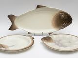 un plat en forme de poisson et deux assiettes sur la table