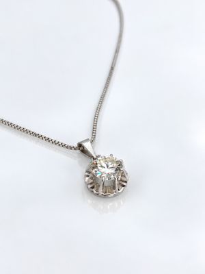 un gros plan d'un collier en diamants posé sur une surface blanche