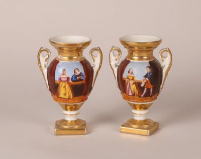 two vases with pictures of people painted on them sitting on top of a table
