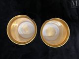 pair of gold and white glass bowls on a black background