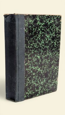 un livre noir parsemé de taches vertes posé sur une surface blanche