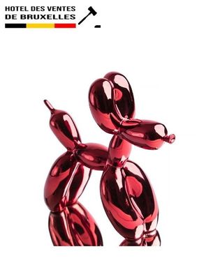 a red balloon dog sculpture on display on a white background