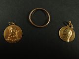 deux médailles d'or et une bague posées sur un fond noir