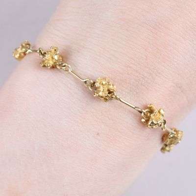 a close up of a person wearing a gold bracelet with flowers on it