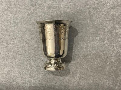 une coupe en argent posée sur une surface grise