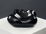 a black sculpture on a white pedestal on a gray background
