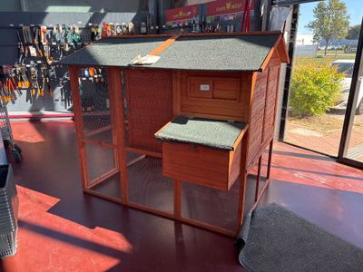 a large wooden chicken coop with a green roof