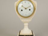 a small white clock with a gold trim on a stand