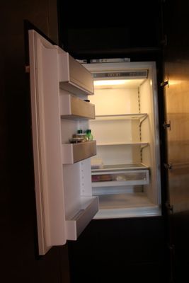 un réfrigérateur dont la porte est ouverte, dans une pièce sombre