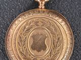 an old gold pocket watch with a chain on a black surface