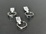 three rings with a blue topaz and a white topaz are sitting on a black surface