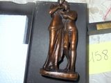 une statue en bronze représentant un homme et une femme, posée sur une table