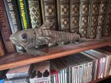 une statue de poisson posée sur une étagère devant de nombreux livres