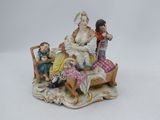une figurine représentant une femme assise sur un lit avec deux enfants