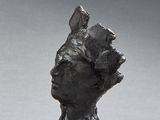 a small statue of a woman sitting on a wooden block