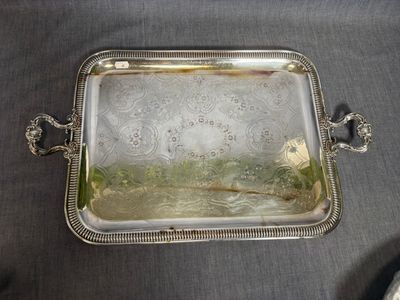 un plat ancien en argent avec des poignées, posé sur une table