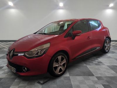 une voiture rouge est garée dans une pièce au sol en damier